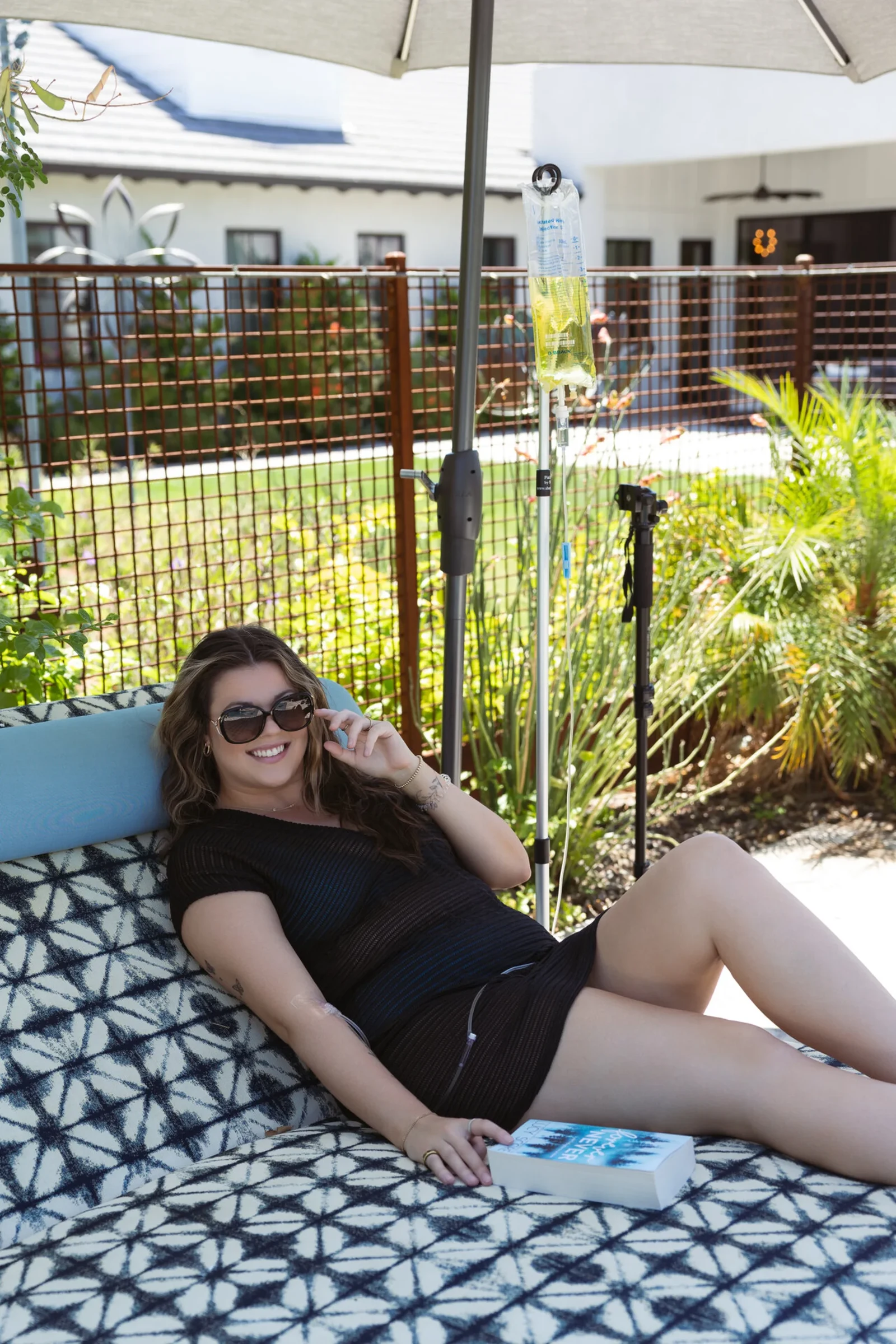 A woman in sunglasses stretched out on a patio daybed on a warm afternoon, partway through her treatment