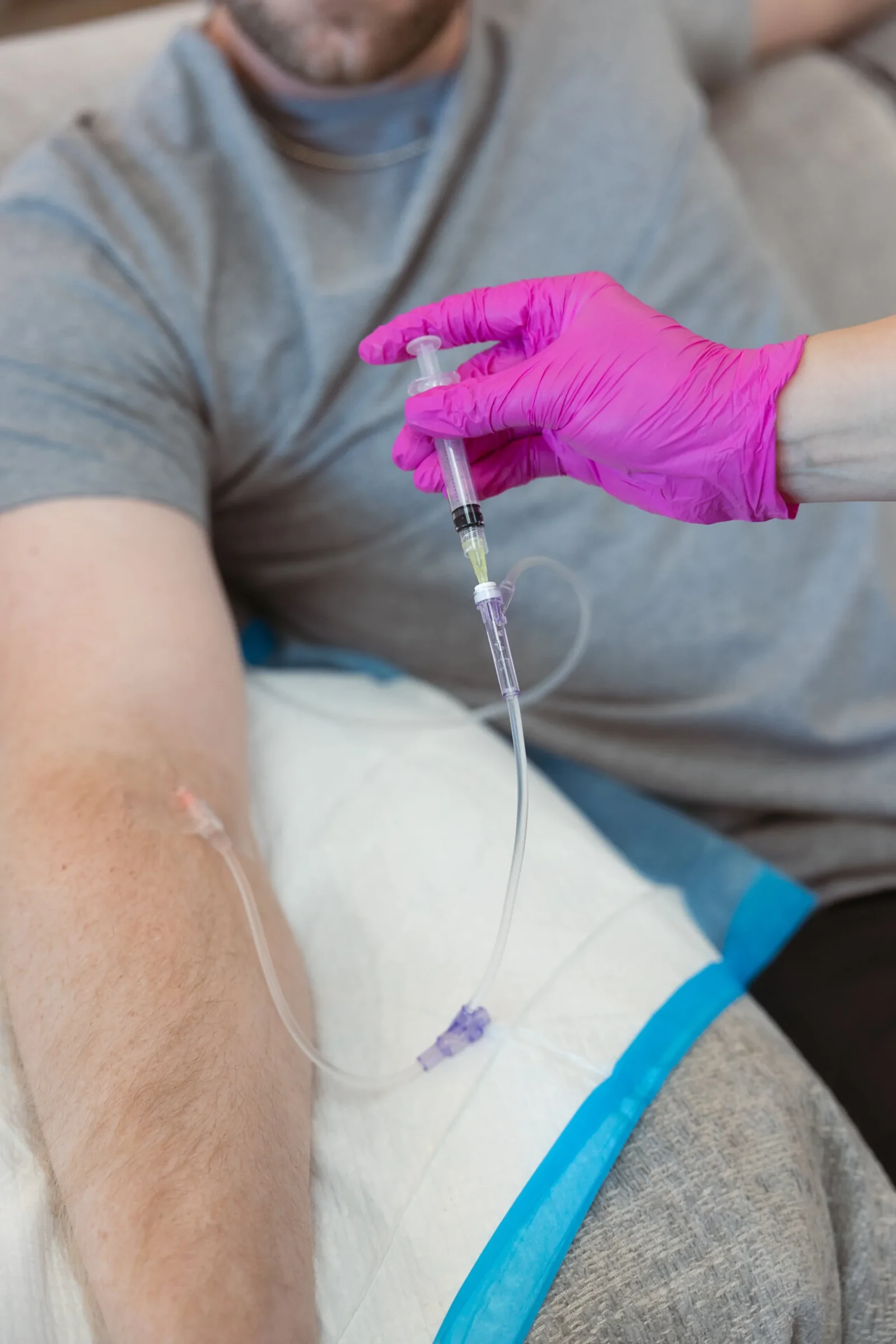 Close-up of a gloved hand securing the line where it enters the forearm, the dressing already taped