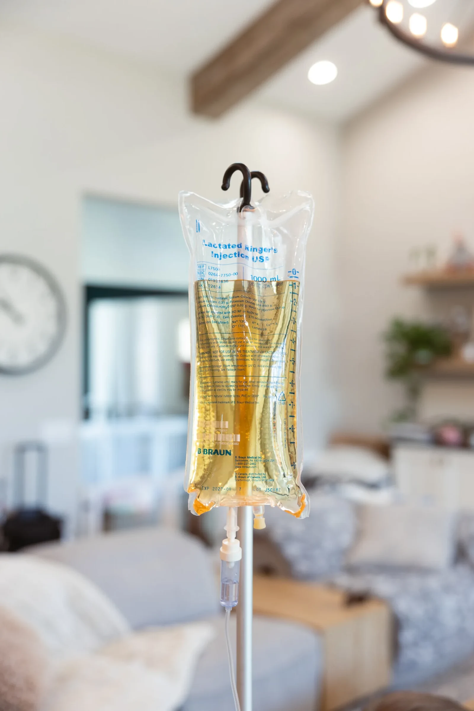 A vitamin drip hanging ready on its stand in a Phoenix living room, the sofa made up behind it