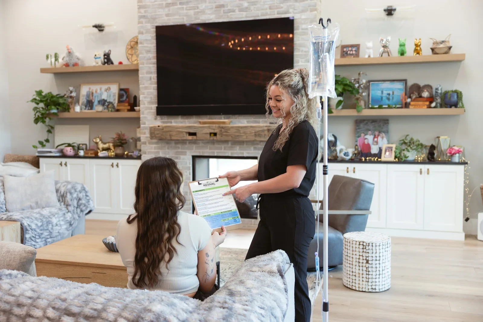 A registered nurse going through the health history with a client seated on her own sofa, the IV stand ready beside them