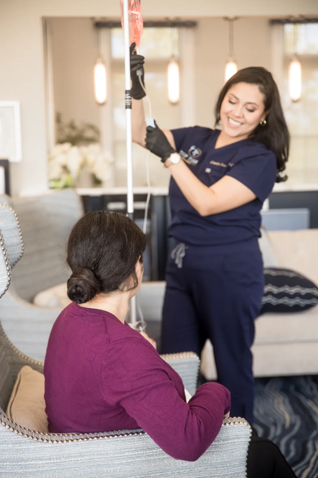 A Top Tier clinician talking with a client during an IV drip in a home armchair