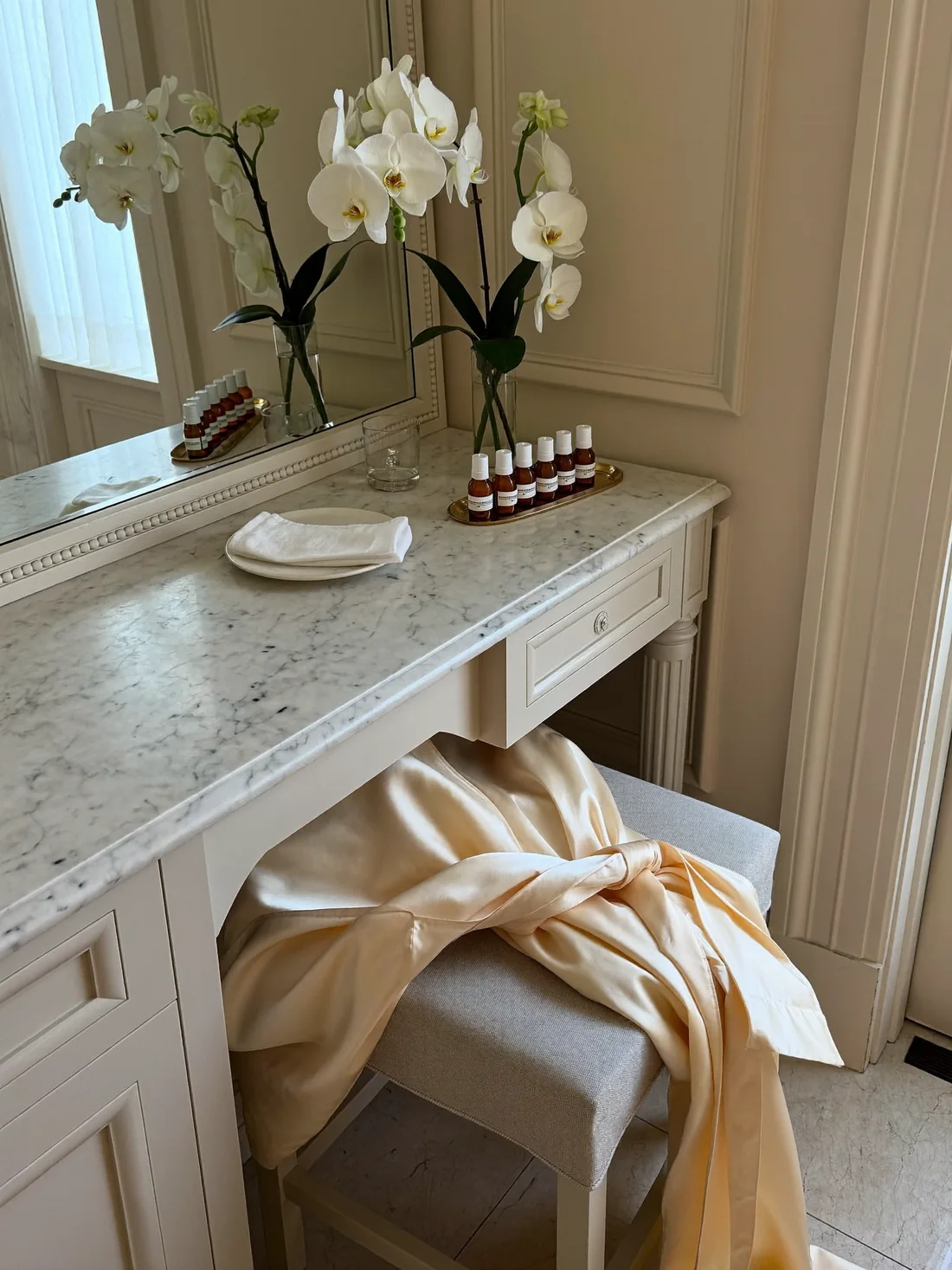 A marble vanity with a silk robe, a white orchid stem and a folded linen towel